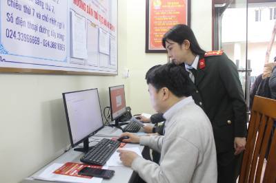 Cán bộ Công an thành phố Hà Nội hướng dẫn người dân thực hiện các thao tác giải quyết thủ tục cấp Phiếu lý lịch tư pháp. Ảnh: Nguyễn Thắng - TTXVN