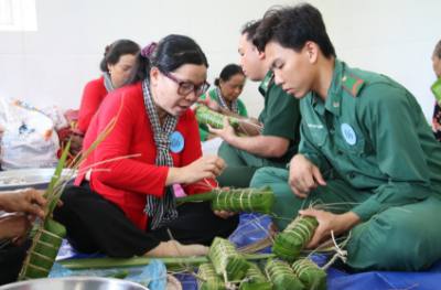 Phụ nữ Bến Tre và các cán bộ, chiến sĩ biên phòng cùng nhau quây quần gói bánh tét, thắt chặt tình quân dân. Ảnh: Chương Đài - TTXVN