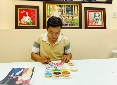 Anh Khưu Tấn Bửu (sinh năm 1995), chủ mô hình khởi nghiệp tranh gạo Tấn Bửu hoàn thiện tác phẩm tranh gạo về Chủ tịch Hồ Chí Minh. Ảnh: TTXVN phát