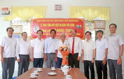 Bí thư Tỉnh ủy Cà Mau Nguyễn Hồ Hải tặng hoa chúc mừng đảng viên Vũ Khắc Trung vinh dự nhận Huy hiệu 80 năm tuổi Đảng. Ảnh: Huỳnh Anh - TTXVN