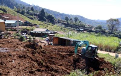 Máy móc tham gia tạo mặt bằng để xây nhà mới giúp dân thôn Chung Tam định cư tại nơi ở mới an toàn hơn. Ảnh: Cao Nguyên-TTXVN
