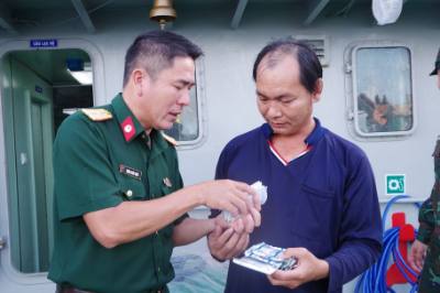Quân y của tàu BV 98308 TS hướng dẫn sử dụng và phát thuốc cho ngư dân Võ Hoàng Rớt. Ảnh: TTXVN phát 