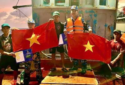 Cán bộ, chiến sĩ Vùng 2 Hải quân tuyên truyền, tặng cờ cho ngư dân trên biển. Ảnh: TTXVN phát 